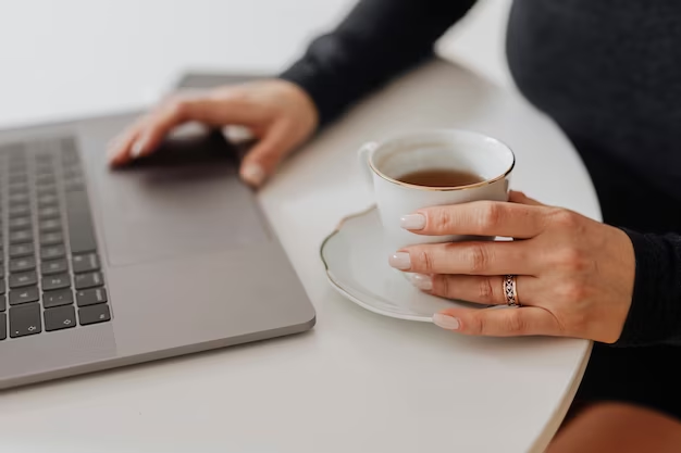 Starting an online business - a person typing on a laptop keyboard with a cup of coffee on the side