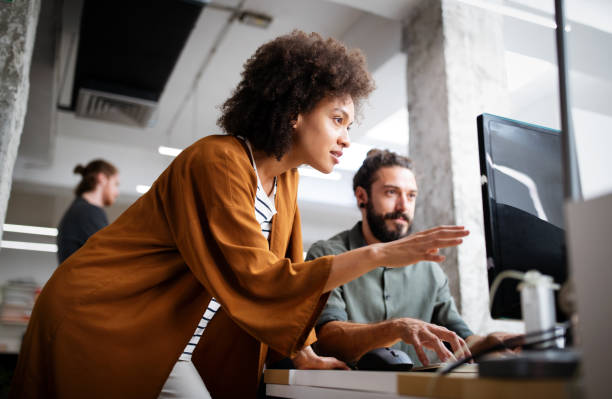 Two colleagues discuss financial planning strategies while working on a computer in a modern office.