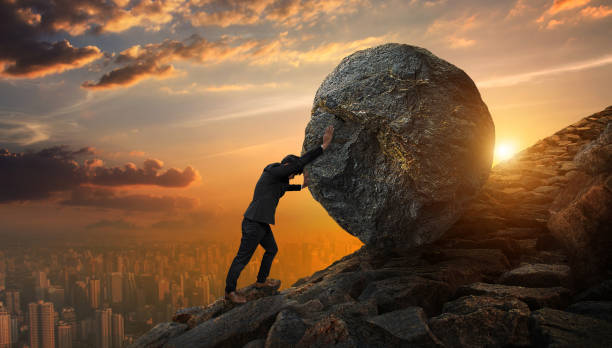 A businessman pushes a large rock uphill, symbolizing the challenges of starting a small business.